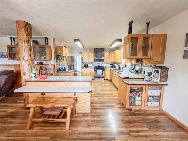 2010 Clemons Rd, Rice, WA 99167 - kitchen featuring stainless steel appliances, light wood-style floors, a peninsula, and glass insert cabinets