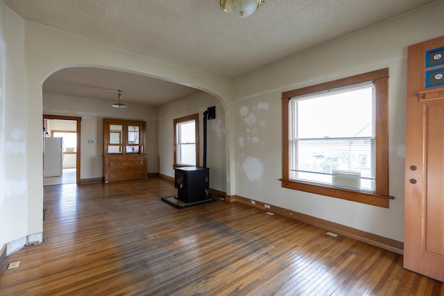 608 S Hatch St, Spokane, WA 99202 - foyer featuring arched walkways, a wood stove, wood-type flooring, baseboards, and a textured ceiling