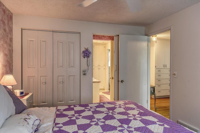 12820 E Sinto Ave, Spokane Valley, WA 99216 - bedroom featuring a baseboard heating unit, a textured ceiling, a closet, ensuite bath, and a ceiling fan