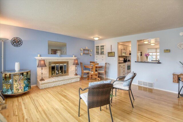 12820 E Sinto Ave, Spokane Valley, WA 99216 - living room featuring a textured ceiling, light wood-style flooring, a glass covered fireplace, and baseboards