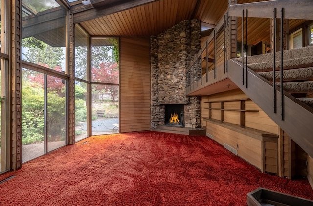 12515 E Apache Pass Rd, Spokane, WA 99206 - unfurnished living room featuring carpet floors, wood walls, high vaulted ceiling, a fireplace, and stairway