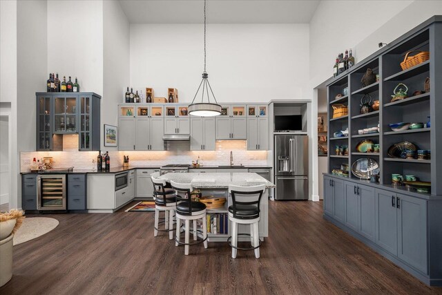 220 E Meadowlane Rd, Spokane, WA 99224 - kitchen featuring appliances with stainless steel finishes, beverage cooler, a towering ceiling, dark wood-style floors, and backsplash