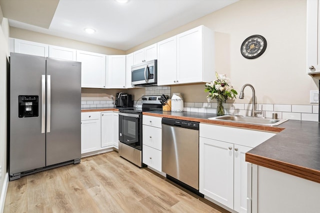 3515 W Excell Ln, Spokane, WA 99208 - kitchen with appliances with stainless steel finishes, a sink, white cabinets, light wood-style flooring, and tasteful backsplash