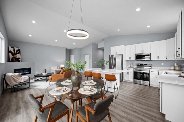 11911 N Main St, Mead, WA 99021 - dining area with vaulted ceiling, wood finished floors, a glass covered fireplace, and recessed lighting