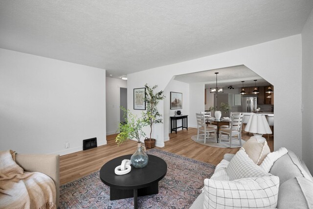 5727 N Cannon St, Spokane, WA 99205 - living area with light wood-style flooring, a chandelier, baseboards, and a textured ceiling