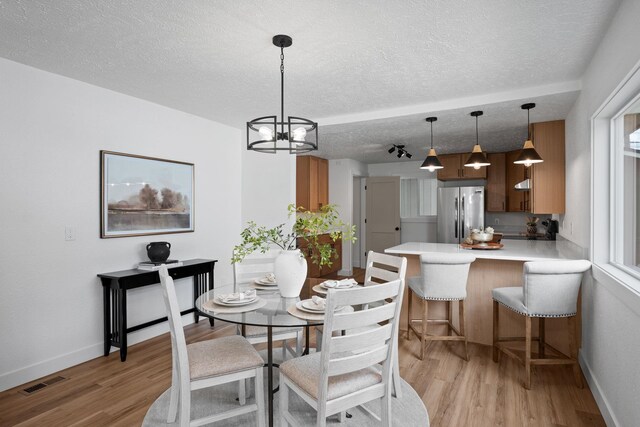 5727 N Cannon St, Spokane, WA 99205 - dining space with light wood-type flooring, a textured ceiling, a chandelier, and baseboards