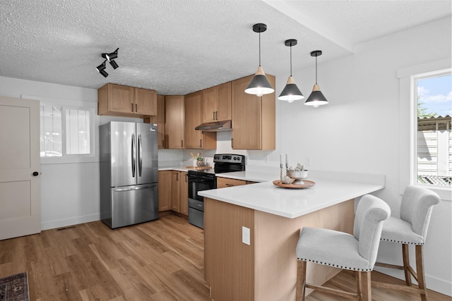 5727 N Cannon St, Spokane, WA 99205 - kitchen featuring freestanding refrigerator, electric stove, a peninsula, under cabinet range hood, and a breakfast bar