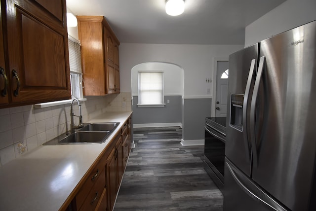 1103 E Longfellow Ave, Spokane, WA 99207 - kitchen with stainless steel appliances, baseboards, a sink, decorative backsplash, and arched walkways