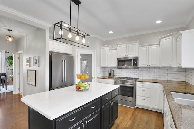 17321 E Morningside Ln, Spokane Valley, WA 99016 - kitchen with stainless steel appliances, dark cabinetry, white cabinetry, arched walkways, and crown molding