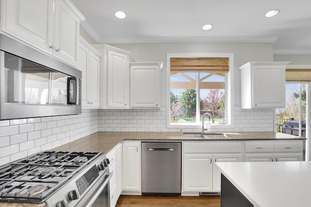 17321 E Morningside Ln, Spokane Valley, WA 99016 - kitchen featuring appliances with stainless steel finishes, a sink, white cabinetry, ornamental molding, and light stone countertops