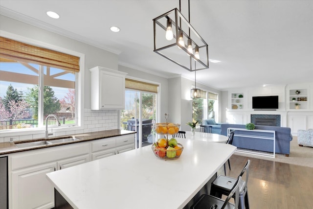 17321 E Morningside Ln, Spokane Valley, WA 99016 - kitchen with a sink, dark wood-style flooring, white cabinetry, a fireplace, and ornamental molding
