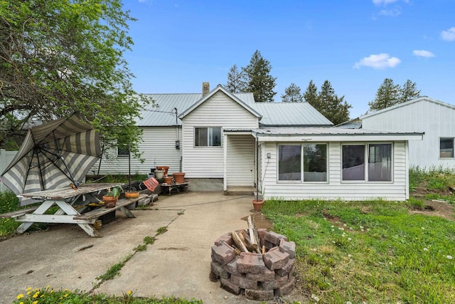 110 N Spokane Ave, Newport, WA 99156 - rear view of property featuring an outdoor fire pit, a patio area, metal roof, and a chimney