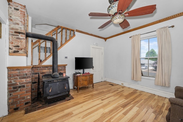 802 10th St, Davenport, WA 99122 - living room with wood finished floors, stairs, a ceiling fan, a wood stove, and crown molding
