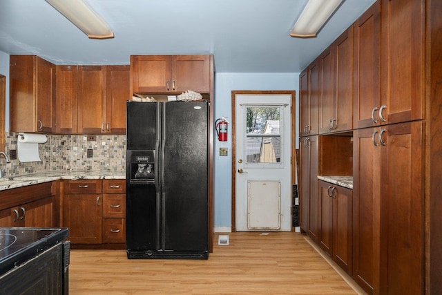802 10th St, Davenport, WA 99122 - kitchen with black appliances, light wood-style flooring, tasteful backsplash, light stone counters, and brown cabinetry