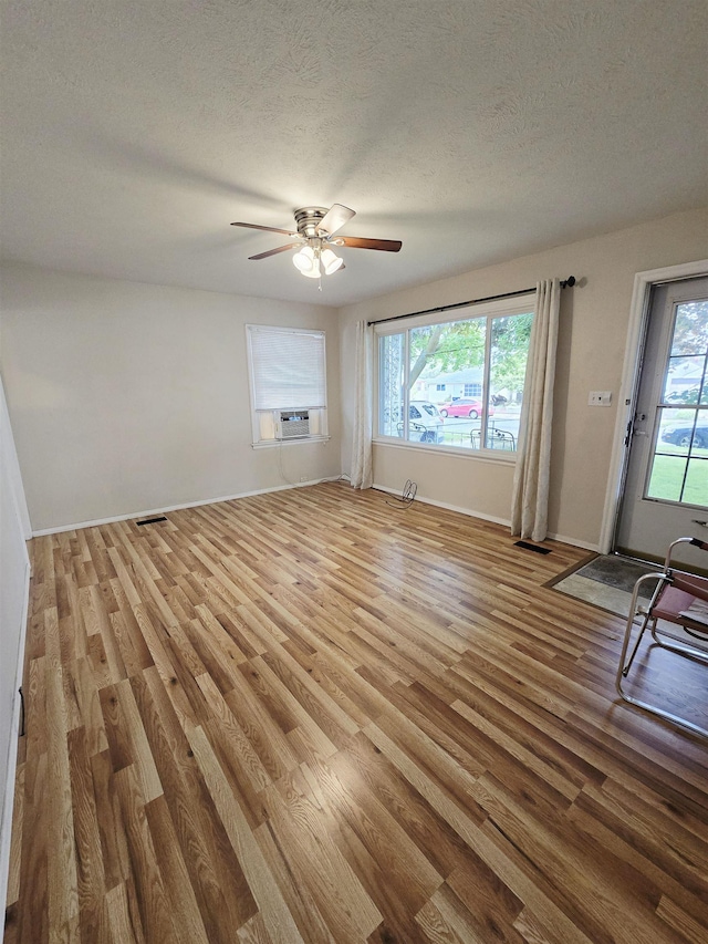 1304 E Hoffman Ave, Spokane, WA 99207 - unfurnished living room featuring wood finished floors, plenty of natural light, a ceiling fan, and a textured ceiling