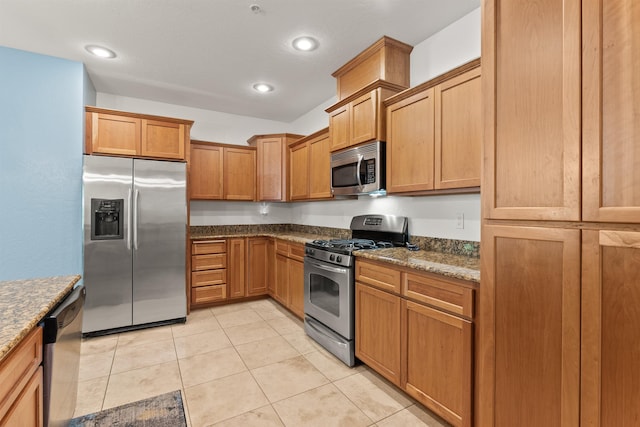 4461 W Greenchain Loop # 5, Coeur D Alene, ID 83814 - kitchen featuring appliances with stainless steel finishes, light tile patterned floors, dark stone counters, recessed lighting, and brown cabinetry