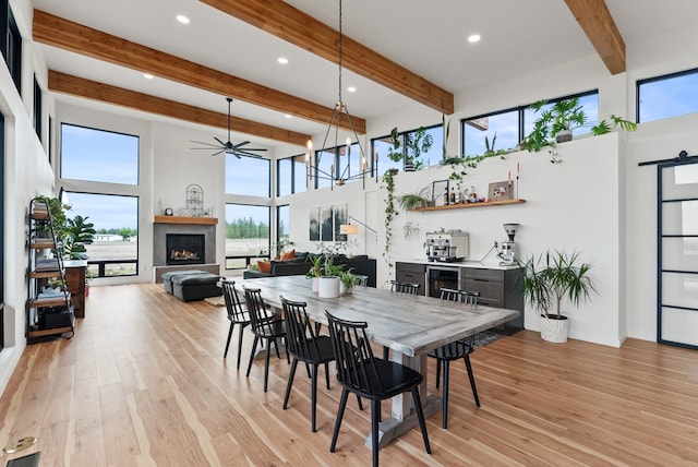 311 N Christensen Rd, Medical Lake, WA 99022 - dining space featuring a lit fireplace, light wood finished floors, beam ceiling, a barn door, and a towering ceiling