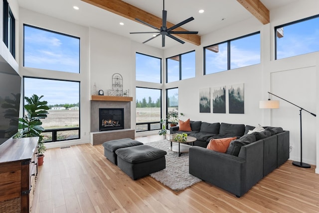 311 N Christensen Rd, Medical Lake, WA 99022 - living area featuring beamed ceiling, a high ceiling, light wood-type flooring, ceiling fan, and a lit fireplace