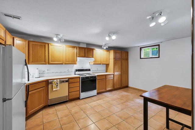 10808 47th Ave, Spokane Valley, WA 99206 - kitchen with white appliances, under cabinet range hood, light countertops, light tile patterned floors, and brown cabinetry
