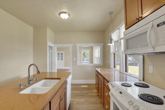 216 6th St, Cheney, WA 99004 - kitchen featuring white appliances, a sink, brown cabinets, light wood finished floors, and plenty of natural light