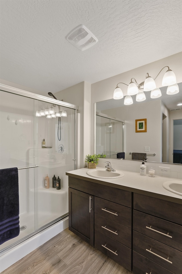 8604 W 8th Ave, Spokane, WA 99224 - bathroom with double vanity, wood finished floors, a stall shower, and a textured ceiling