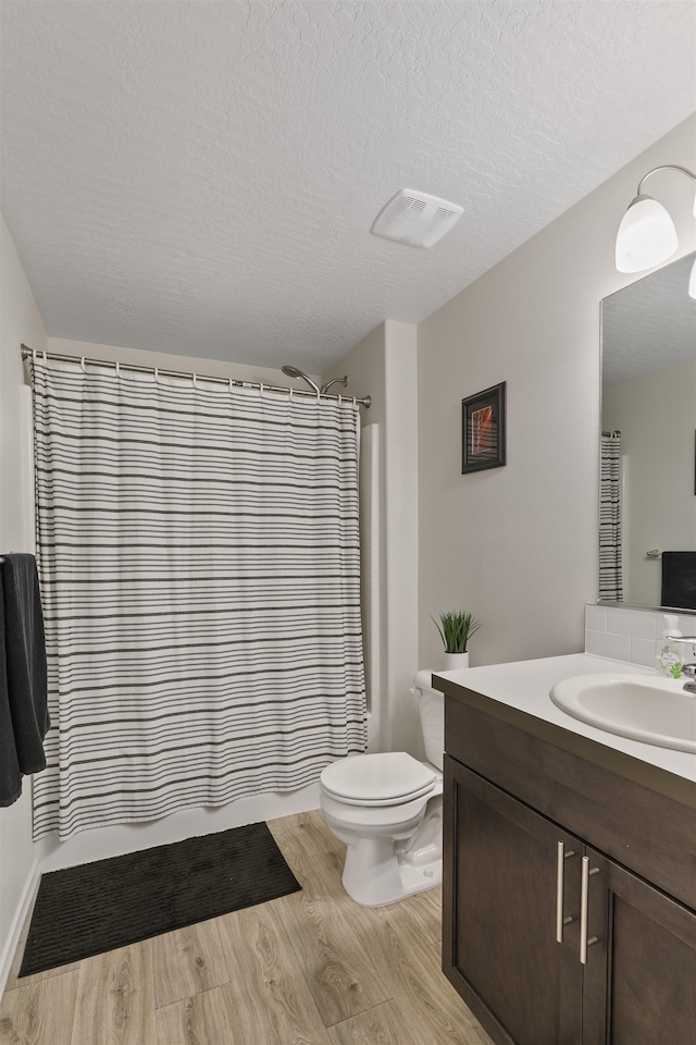 8604 W 8th Ave, Spokane, WA 99224 - bathroom featuring vanity, wood finished floors, toilet, and a textured ceiling
