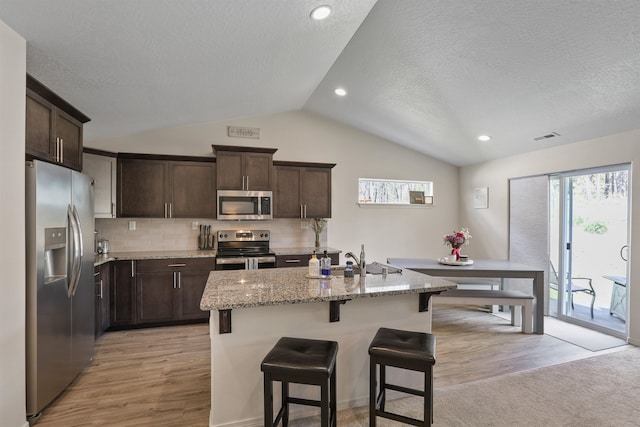 8604 W 8th Ave, Spokane, WA 99224 - kitchen featuring stainless steel appliances, vaulted ceiling, a sink, dark brown cabinets, and light wood finished floors
