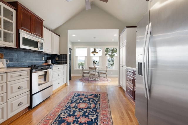 8904 E Boardwalk Ln, Spokane, WA 99212 - kitchen with appliances with stainless steel finishes, ceiling fan, light wood-type flooring, vaulted ceiling, and glass insert cabinets