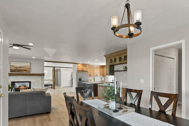14716 E 48th Ln, Veradale, WA 99037 - dining space featuring a chandelier, ceiling fan, a textured ceiling, light wood-style flooring, and a fireplace