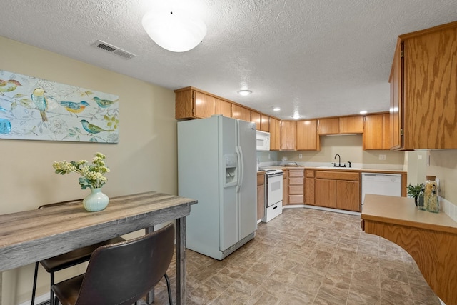 14716 E 48th Ln, Veradale, WA 99037 - kitchen featuring white appliances, light countertops, a textured ceiling, recessed lighting, and brown cabinetry