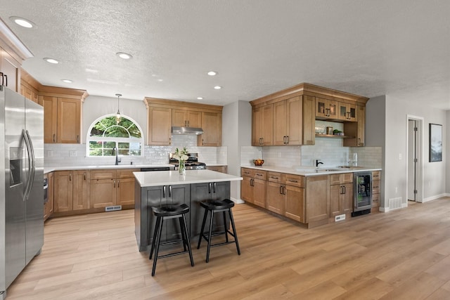 14716 E 48th Ln, Veradale, WA 99037 - kitchen with wine cooler, stainless steel fridge with ice dispenser, stove, under cabinet range hood, and a sink