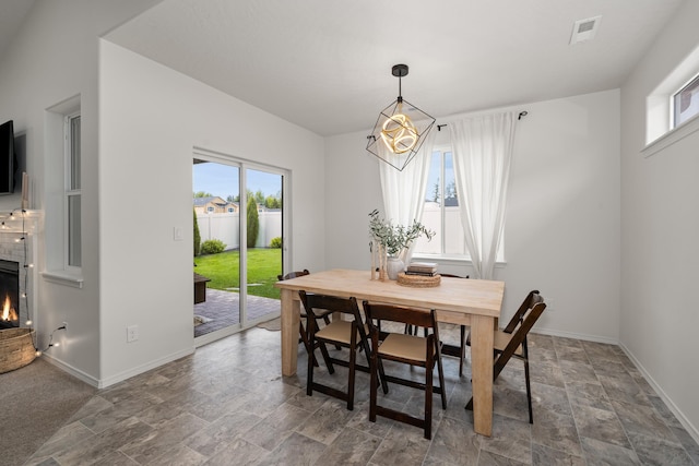 2026 W Parkway Ct, Spokane, WA 99208 - dining space featuring stone finish floors, baseboards, a chandelier, and a warm lit fireplace