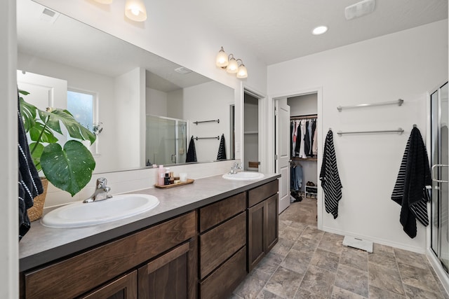 2026 W Parkway Ct, Spokane, WA 99208 - bathroom with a shower stall, a walk in closet, double vanity, baseboards, and stone finish flooring
