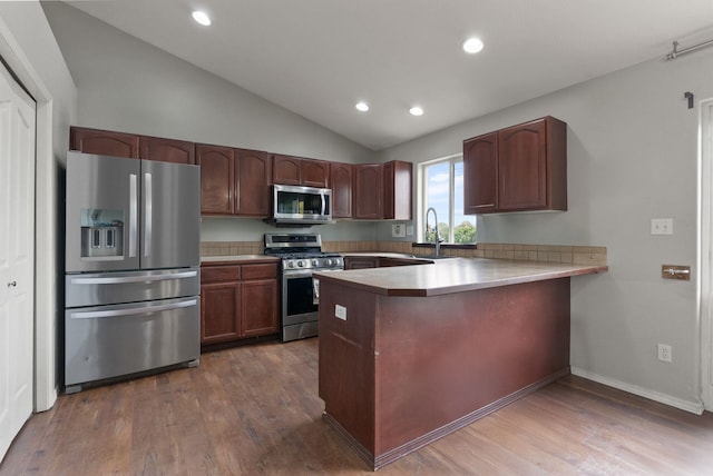 8710 N I Ct, Spokane, WA 99208 - kitchen with appliances with stainless steel finishes, vaulted ceiling, a peninsula, wood finished floors, and light countertops