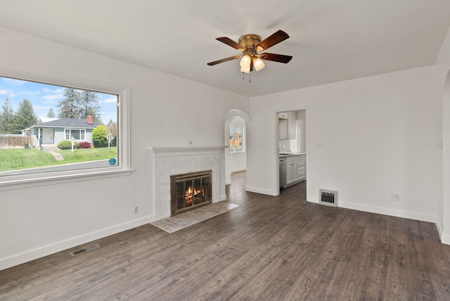 3215 W Longfellow Ave, Spokane, WA 99205 - unfurnished living room with arched walkways, a ceiling fan, a brick fireplace, and baseboards