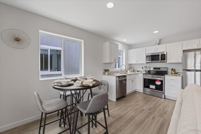 1912 W Buckeye Ave, Spokane, WA 99205 - kitchen with appliances with stainless steel finishes, a sink, light countertops, white cabinetry, and light wood-type flooring