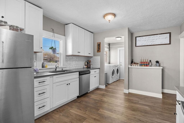 4824 N Stone St, Spokane, WA 99207 - kitchen featuring stainless steel appliances, independent washer and dryer, a sink, dark wood finished floors, and white cabinetry