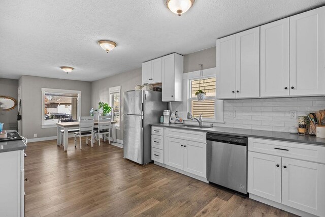 4824 N Stone St, Spokane, WA 99207 - kitchen with stainless steel appliances, a sink, backsplash, a textured ceiling, and dark countertops