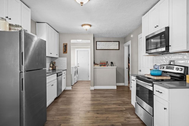 4824 N Stone St, Spokane, WA 99207 - kitchen featuring appliances with stainless steel finishes, dark countertops, decorative backsplash, dark wood-style floors, and white cabinetry