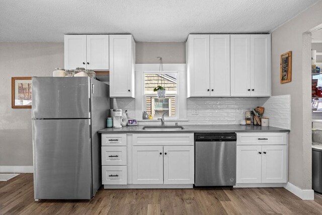 4824 N Stone St, Spokane, WA 99207 - kitchen with appliances with stainless steel finishes, a sink, white cabinetry, wood finished floors, and backsplash