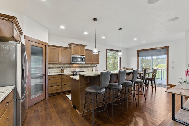 13408 E Copper River Ln, Spokane, WA 99206 - kitchen with stainless steel appliances, brown cabinets, dark wood-type flooring, backsplash, and a kitchen island