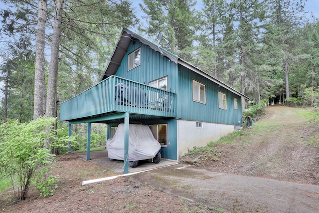4134 Pebble Beach Rd, Loon Lake, WA 99148 - back of house with a wooden deck, driveway, board and batten siding, and a carport