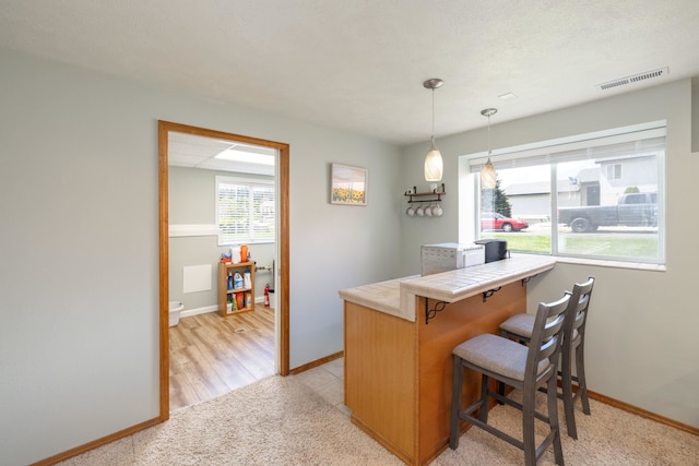 4701 E 13th Ave, Spokane Valley, WA 99212 - kitchen featuring tile countertops, a kitchen bar, baseboards, and a peninsula