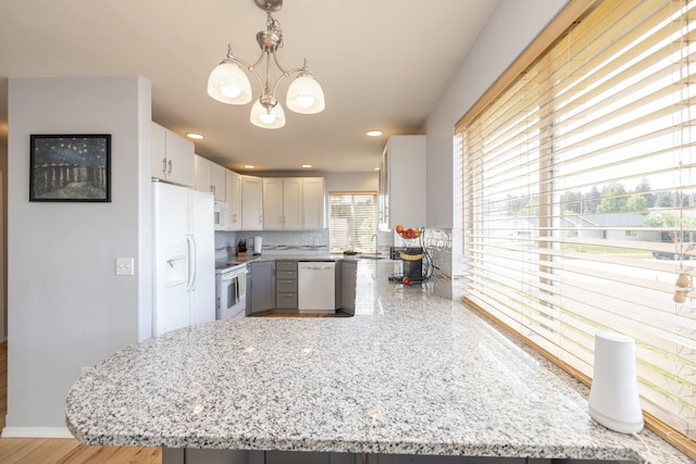 4701 E 13th Ave, Spokane Valley, WA 99212 - kitchen featuring white appliances, a peninsula, a chandelier, and light stone counters