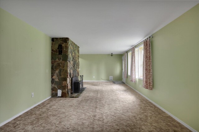 2111 W Mason Rd, Deer Park, WA 99006 - unfurnished living room featuring a wood stove, carpet flooring, and baseboards