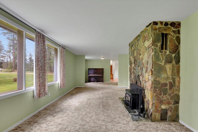 2111 W Mason Rd, Deer Park, WA 99006 - unfurnished living room featuring a wood stove, carpet floors, and baseboards