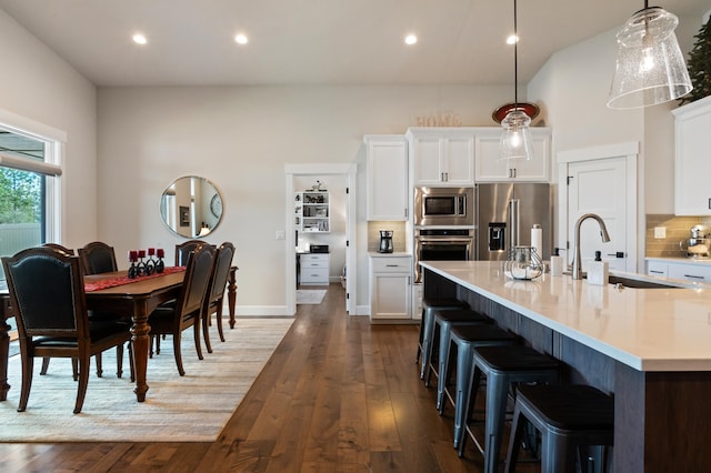 7203 S Tangle Heights Dr, Spokane, WA 99224 - kitchen featuring appliances with stainless steel finishes, light countertops, decorative backsplash, a kitchen breakfast bar, and dark wood-type flooring