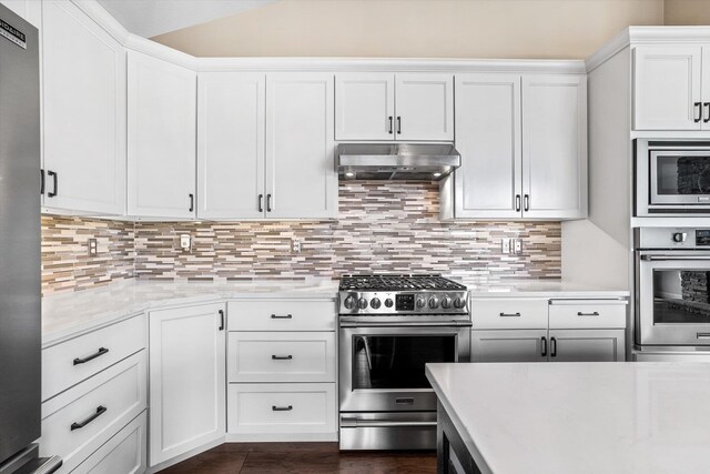 4305 S Bernson Ln, Spokane, WA 99223 - kitchen with stainless steel appliances, under cabinet range hood, lofted ceiling, white cabinetry, and tasteful backsplash