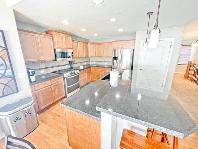 1602 S Canyon Woods Ln, Spokane, WA 99224 - kitchen with appliances with stainless steel finishes, light brown cabinets, backsplash, a spacious island, and recessed lighting