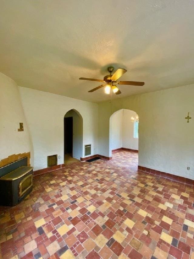 4410 Williams Valley Rd, Clayton, WA 99110 - unfurnished living room featuring arched walkways, ceiling fan, a wood stove, and baseboards
